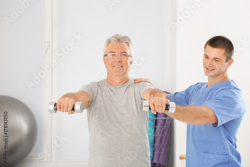 Physiotherapist working with senior patient in modern clinic