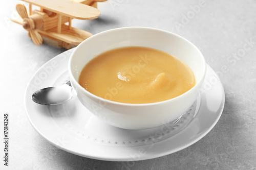 Ceramic bowl with baby food on grey background