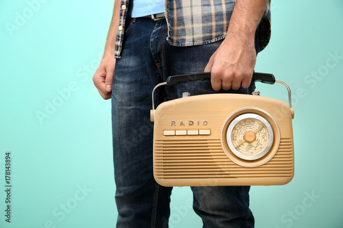 Young man holding retro radio on color background