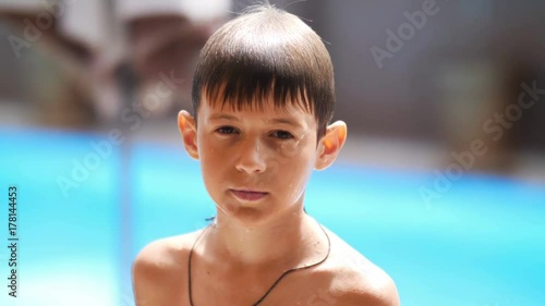 wet serious boy after a swimming pool looks at the camera