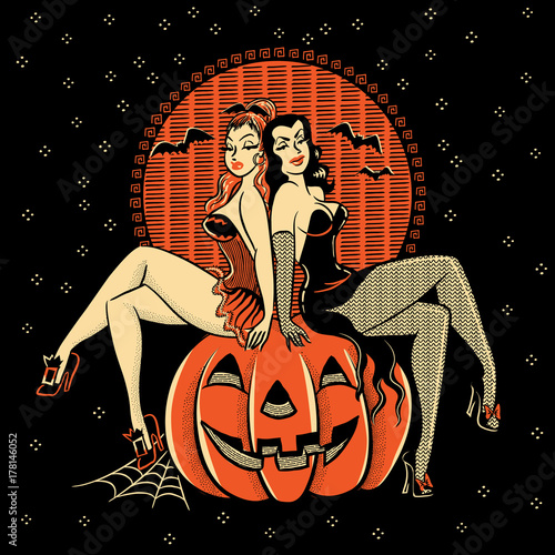 Spooky Halloween glamour twins sitting on a carved pumpkin head. photo