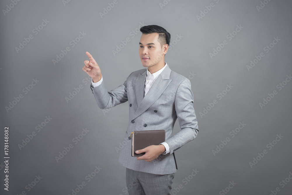 Businessman is touching virtual screen, portrait in studio grey background Businessman is touching virtual screen, portrait in studio grey background