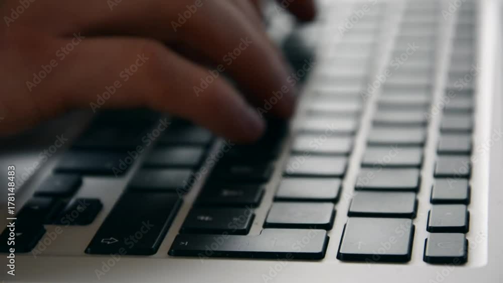 Typing on a laptop keyboard from the side as a close up Typing on a laptop keyboard from the side as a close up
