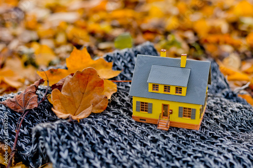 Mini yellow house in the autumn foreat with craft notebook. Cozy home concept photo