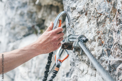 close up of a male climber hooking his carabiner in a safety steel rope