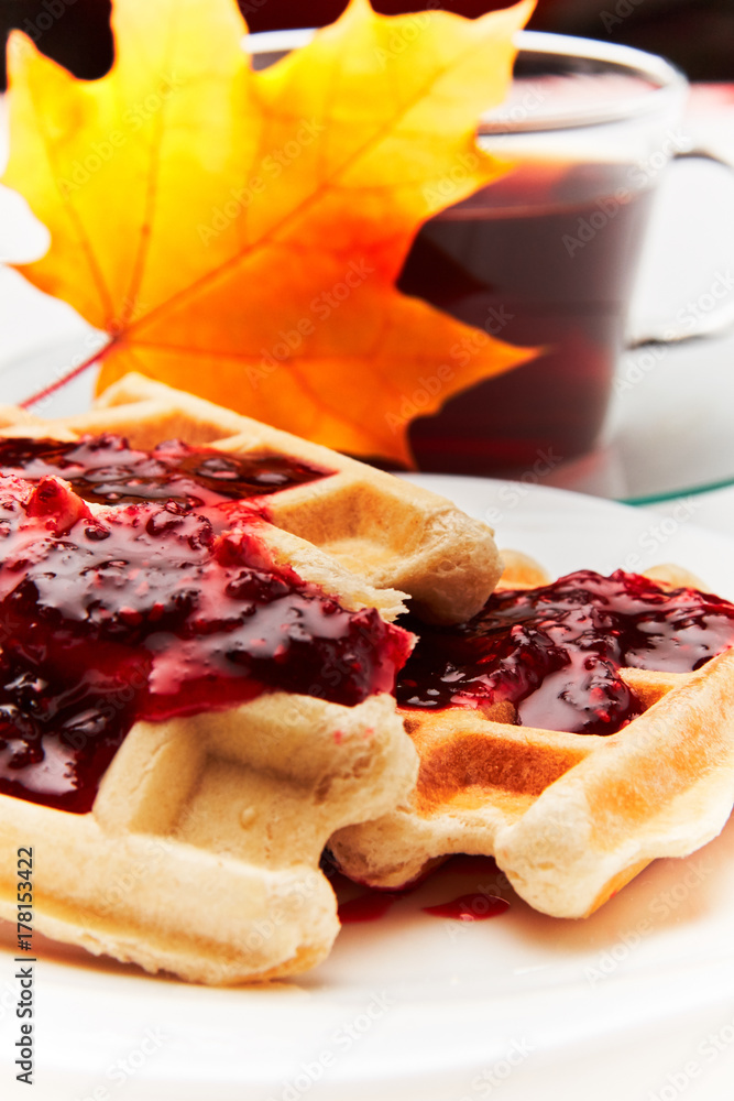 A cup of tea and crispy wafers./A cup of tea and crispy wafers poured with raspberry jam. White dishes. White background. A cup of tea and crispy wafers./A cup of tea and crispy wafers poured with raspberry jam. White dishes. White background.