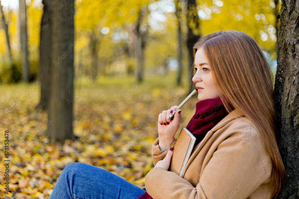 Girl sitting in the autumn park and dreaming about your life with notes concept