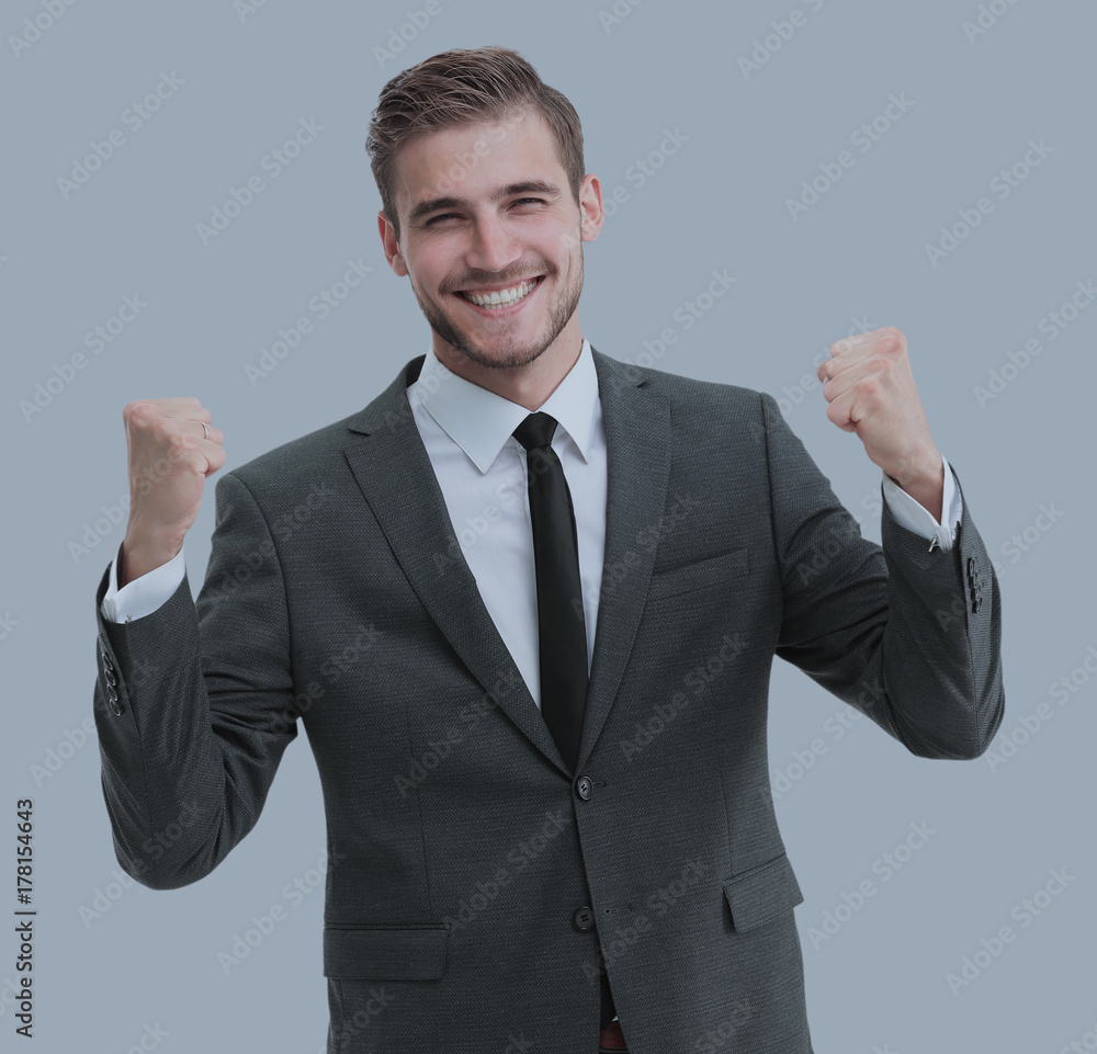Excited smile business man raised arms, isolated over gray backg Excited smile business man raised arms, isolated over gray backg