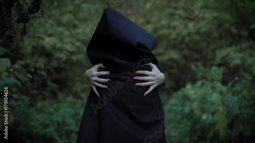 possessed by demons woman is walking in a forest, holding her shoulders by hands with sharp vivid claws