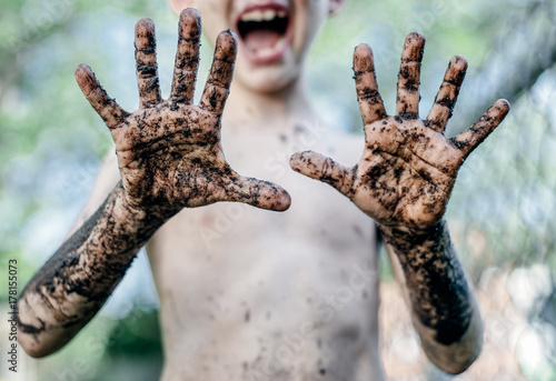 Happy, messy child shows off his very muddy hands