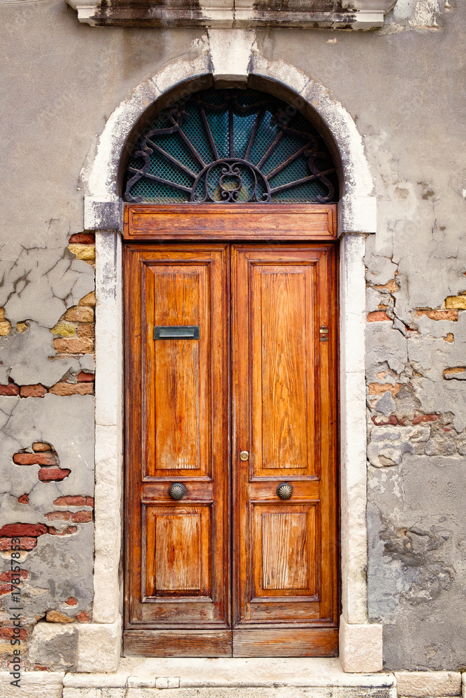 Fototapeta premium Vintage wooden door on an old wall with exposed bricks