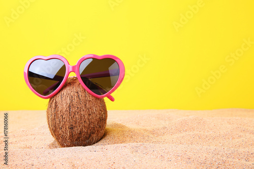 Coconut with sunglasses on the beach sand