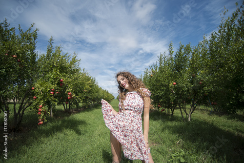 Young woman wearing floral long dress and pose among a pomegranate field photo