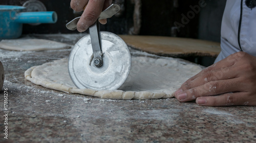 Chef is cutting pizza dough at commercial kitchen