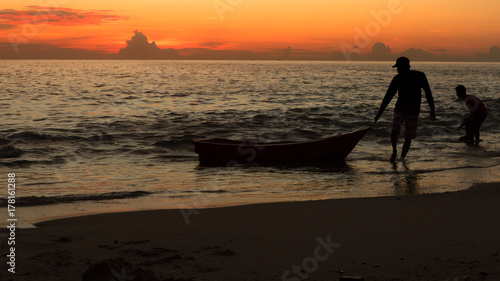 Fisherman and boat over sunset sky