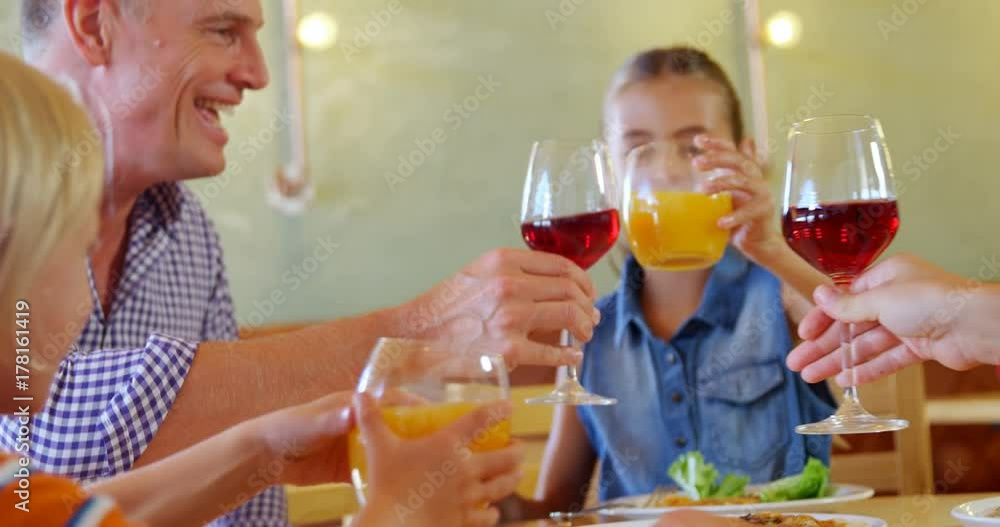 Family toasting glass of wine and juice in restaurant Family toasting glass of wine and juice in restaurant