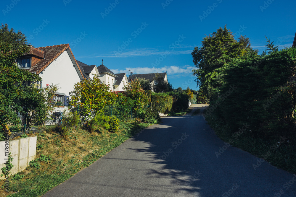 Country houses with green fences and streets in the region of Normandy, France. Beautiful countryside, lifestyle and typical french architecture, european country landscapes.