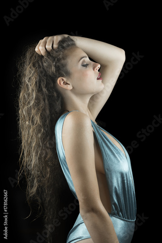 Wet look from a cute woman, studio in black background, wet skin and hair, wear blue shine one piece swimsuit