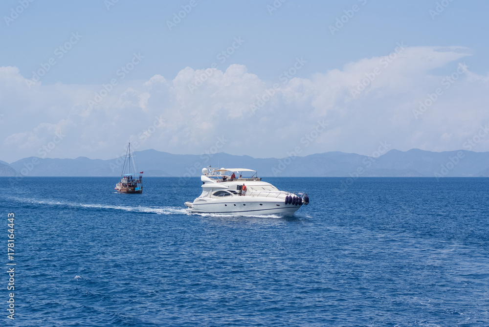 white modern yacht sails on the blue sea against the shore
