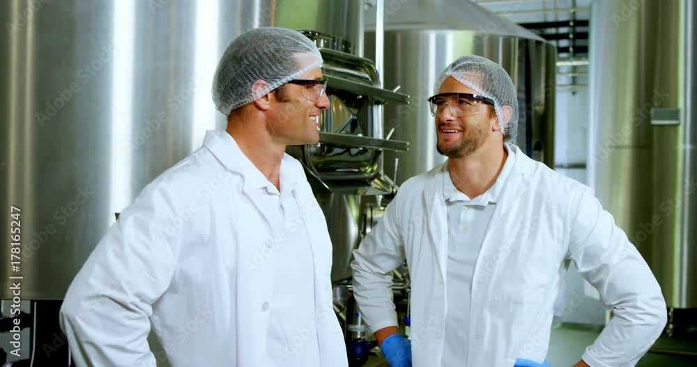 Two brewers interacting with each other at brewery factory Two brewers interacting with each other at brewery factory