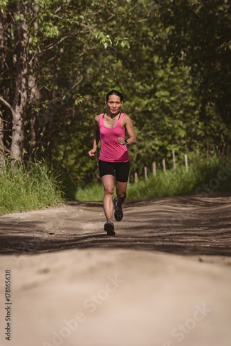 Fit woman jogging in forest road photo