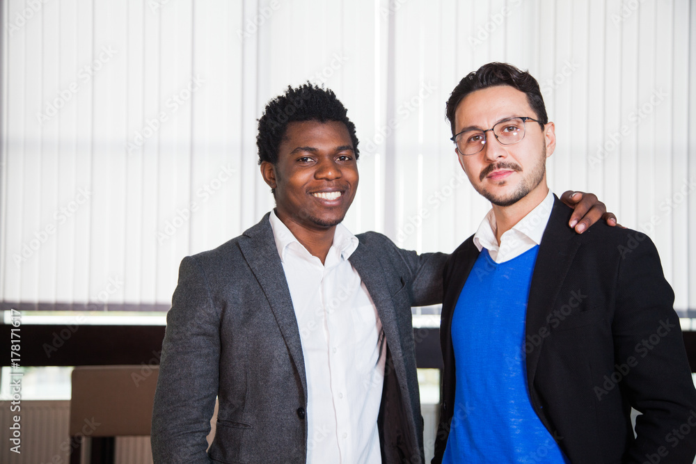 Two smiling men in suits look at camera, portrait of businessmen. Happy guys at office Two smiling men in suits look at camera, portrait of businessmen. Happy guys at office