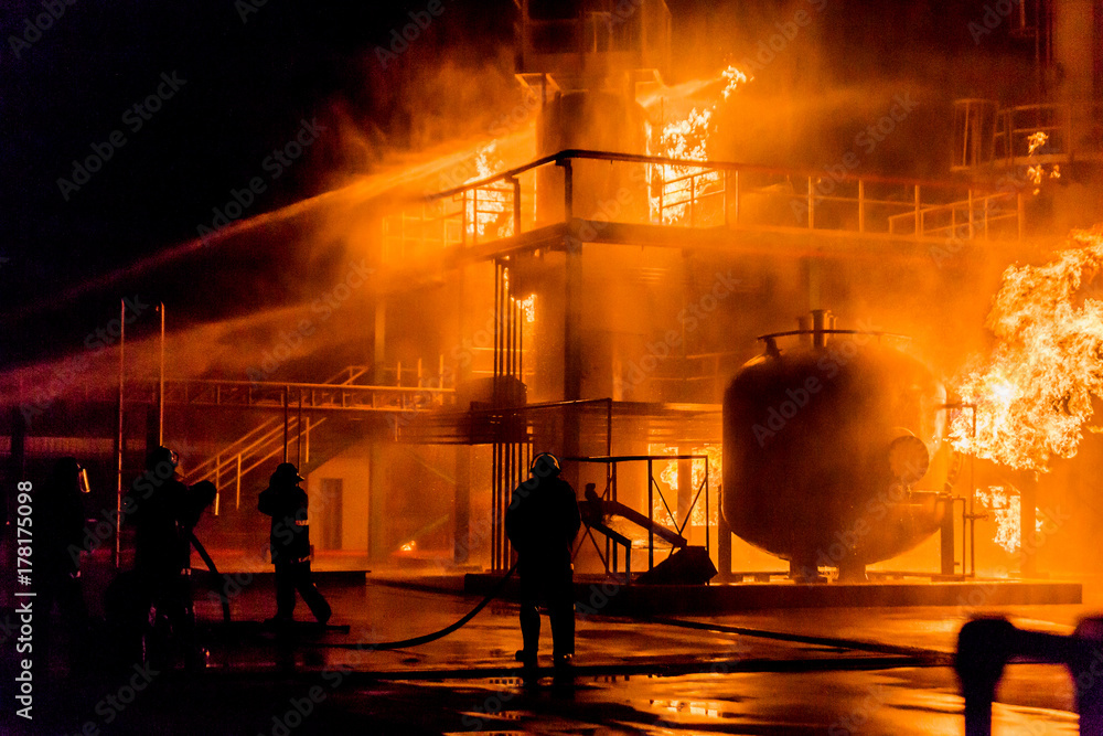 Obraz premium Firemen using water from hose for fire fighting at firefight training of insurance group. Firefighter wearing a fire suit for safety under the danger case.