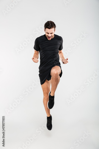 Full length portrait of a cheerful pleased sportsman jumping