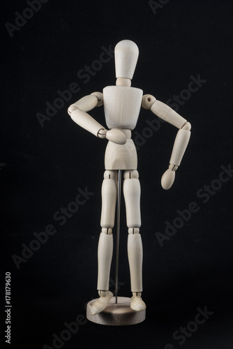 a wooden dummy posing   on a black background	