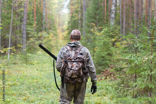 hunter in camouflage with hunting gun in the forest