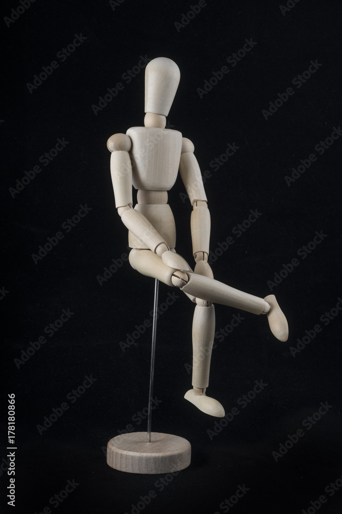 a wooden mannequin in sitting position with a black background a wooden mannequin in sitting position with a black background