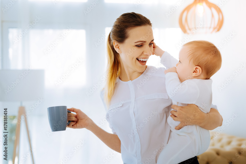 Positive mother drinking tea with her child