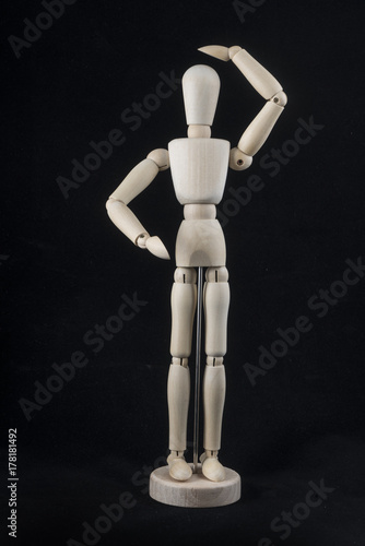 a wooden dummy posing with a hand on the head	