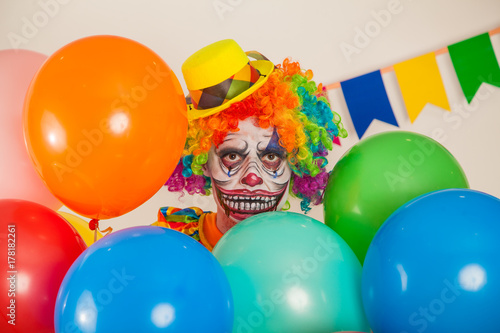 a terrible clown. Halloween. A crazy clown among balloons. Childish fear