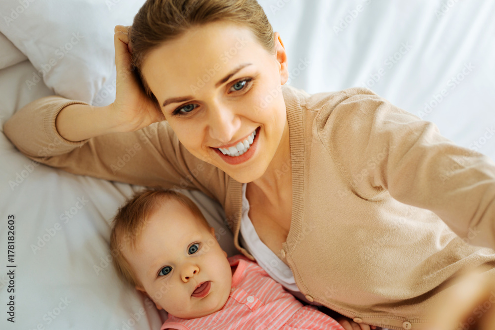 Positive mother making funny faces with her little baby Positive mother making funny faces with her little baby
