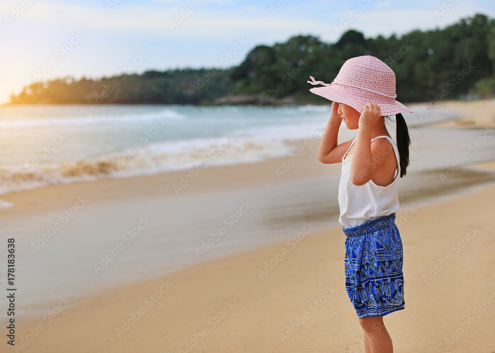 Adorable little girl wear straw hat relax at the beach.