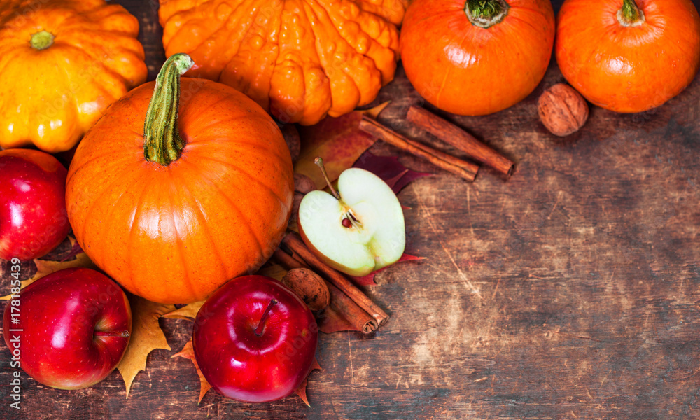 Harvest or Thanksgiving background with pumpkins, apples and fallen leaves on wooden background with copyspace. Halloween, Thanksgiving day or seasonal autumnal concept. Harvest or Thanksgiving background with pumpkins, apples and fallen leaves on wooden background with copyspace. Halloween, Thanksgiving day or seasonal autumnal concept.