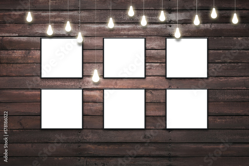 Rustic wooden plank wall with isolated white posters in black frames photo