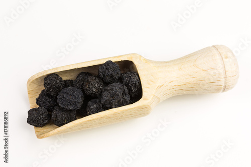 dried black aronia berries with wooden scoop  - aronia arbutifolia photo