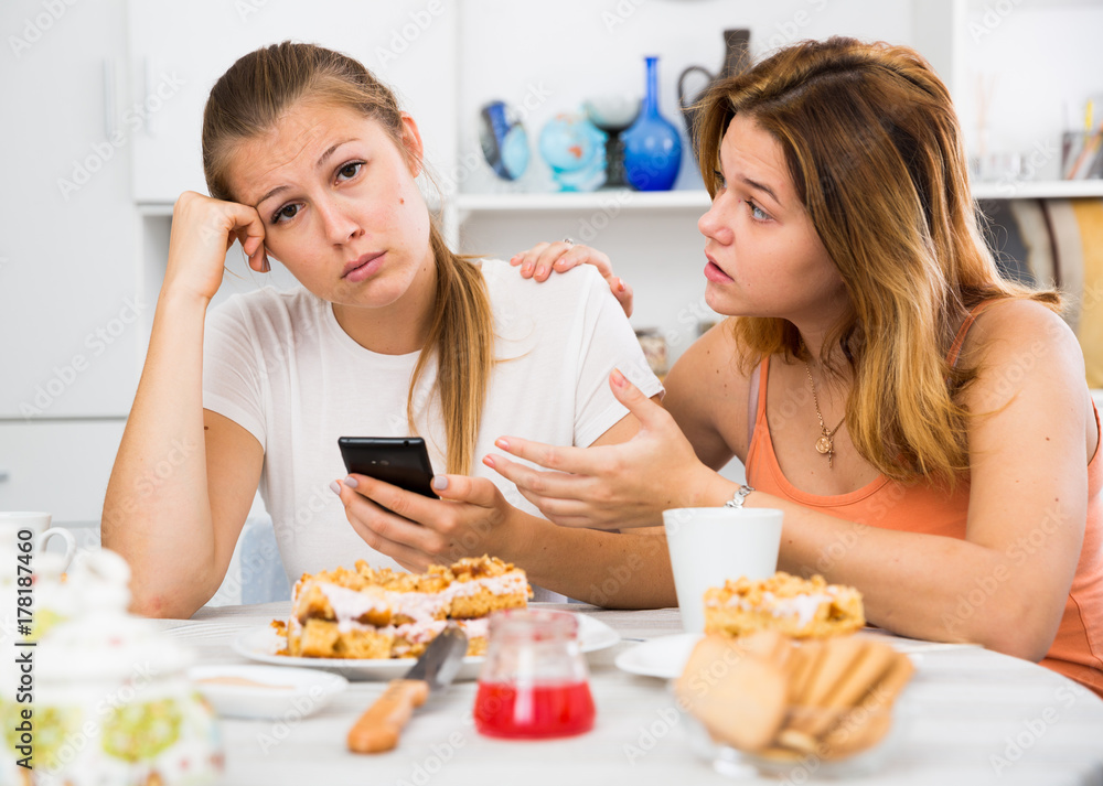 female talking with sad friend with mobile