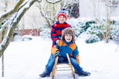 Two little kid boys enjoying sleigh ride in winter