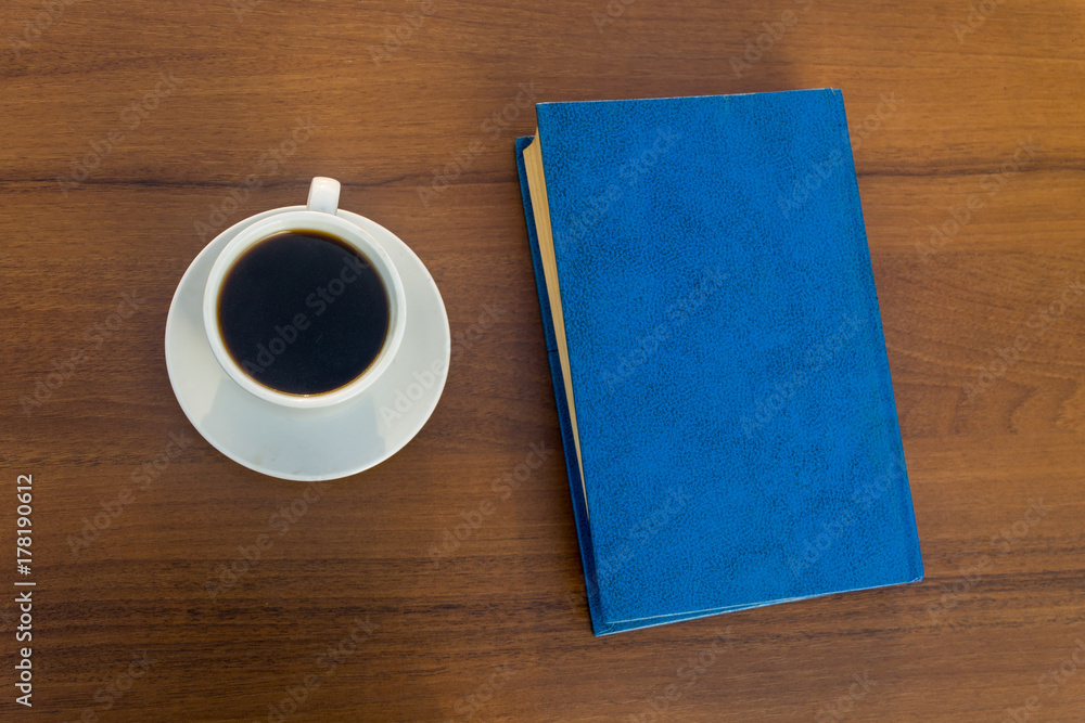 Cup of coffee and closed book on wooden table Cup of coffee and closed book on wooden table