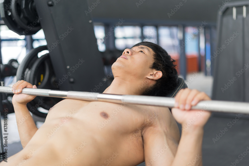 Fitness man in training showing exercises with barbells in gym Fitness man in training showing exercises with barbells in gym
