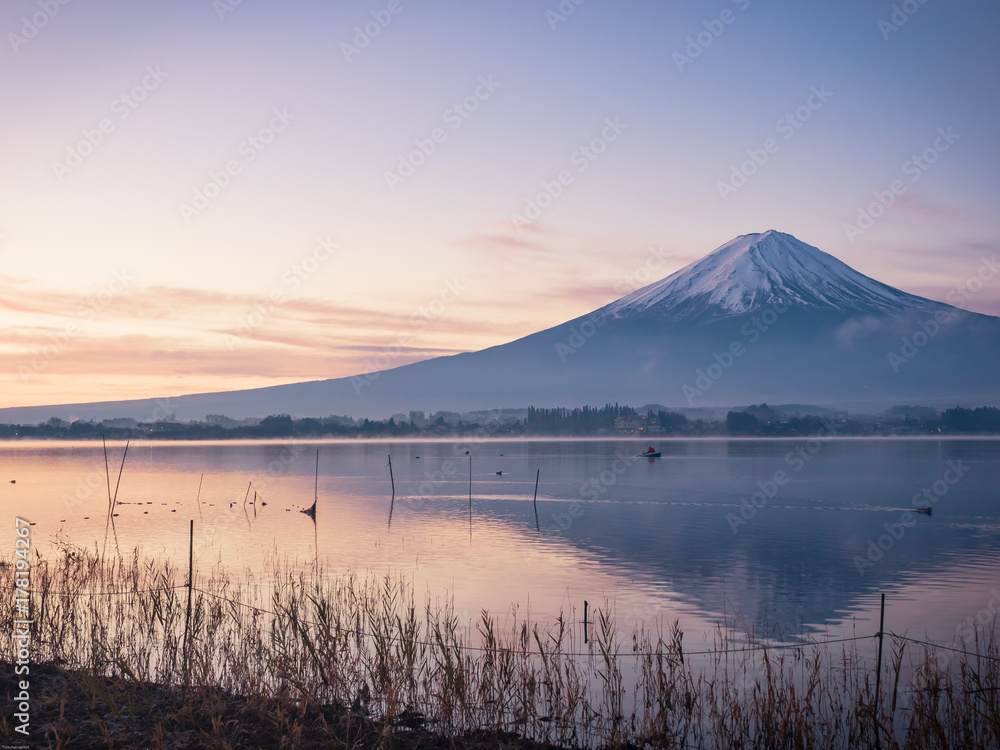 sunrise landscape view from kawaguchi lake with motion blur from group of duck and boat foreground and fuji mountain background with fog from japan