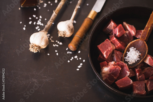 Beef chuck stew ingredients Irish raw Beef Stew Recipe ingredients in cast iron black table spread salt garlic overhead