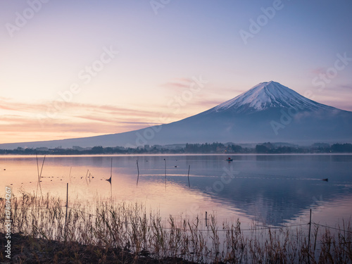 sunrise landscape view from kawaguchi lake with motion blur from group of duck and boat foreground and fuji mountain background with fog from japan