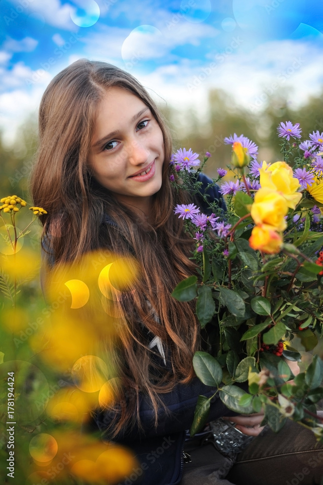 Naklejka premium A good young girl resting in the garden and collecting flowers yellow roses and others