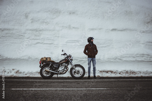 Man with motorcycle in snowy road photo