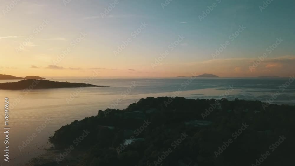 Sunrise bay in tropical island with reflected calm water and clouds aerial shot Sunrise bay in tropical island with reflected calm water and clouds aerial shot