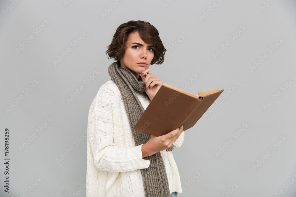 Serious young woman wearing scarf reading book. Serious young woman wearing scarf reading book.